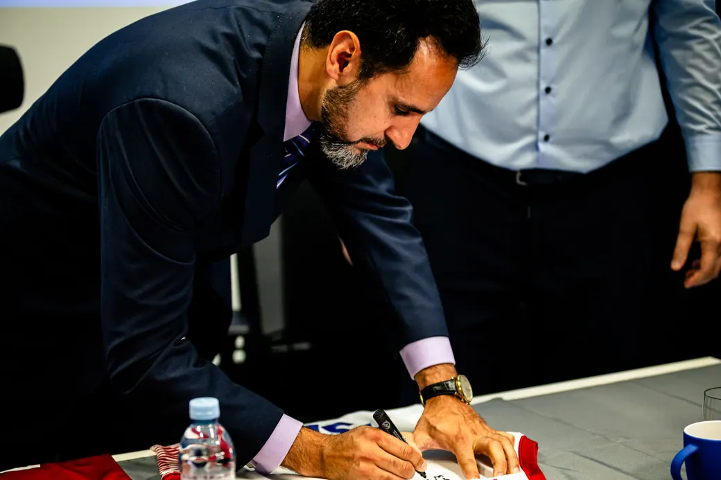 Gabriel Makki signing a jersey at a partnership event